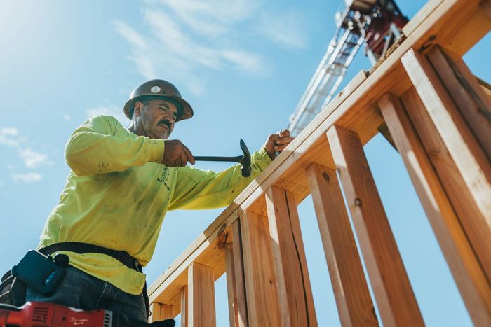 Zimmerer mit Helm richtet ein Holzgerüst